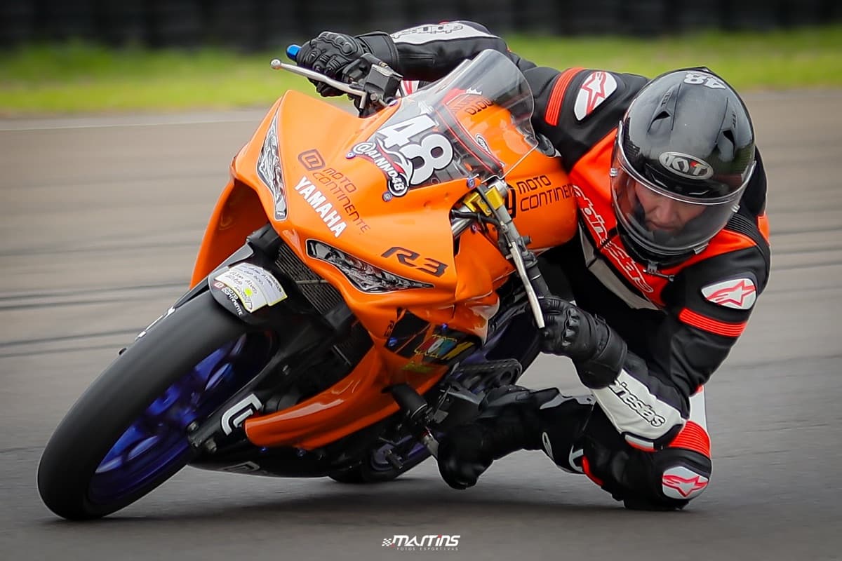 Piloto #48 na Yamaha R3 laranja em curva no autodromo